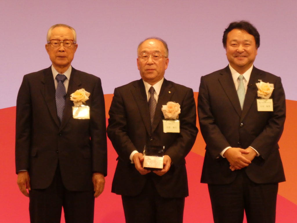  記念撮影する高橋社長（中央）と今井審議会会長（左）、山本社長