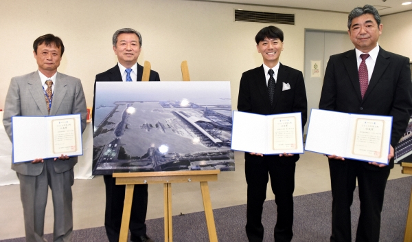  記念撮影する（左から）猪本正道整備士、丸山昌宏社長、幾島健太郎記者、小宮山和秀機長