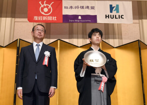  就位式で産経新聞社の近藤哲司社長(左)から賞杯を受けた藤井聡太棋聖（産経新聞社提供）