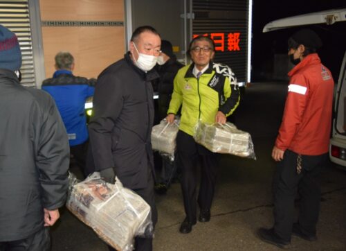  到着した元旦号の梱包をセンター内に運ぶ東根社長（右から２人目）。左は北村茂樹販売局長