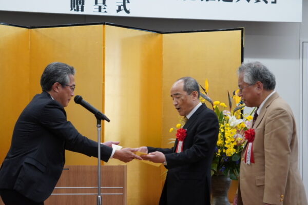  表彰状を渡す斎藤理事（左）と日本点字図書館の立花館長（中央）