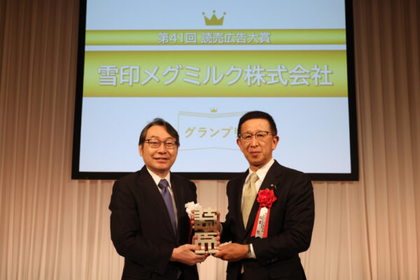  村岡社長（左）からトロフィーを受け取った稲葉常務