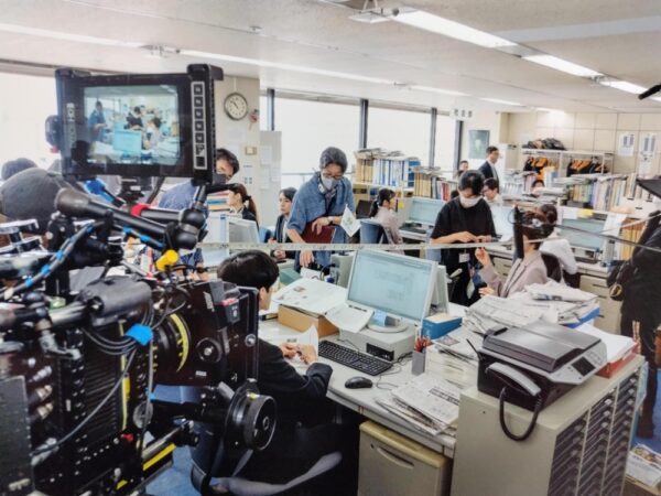  東京本社販売局で撮影の指示をする阪本順治監督（中央）