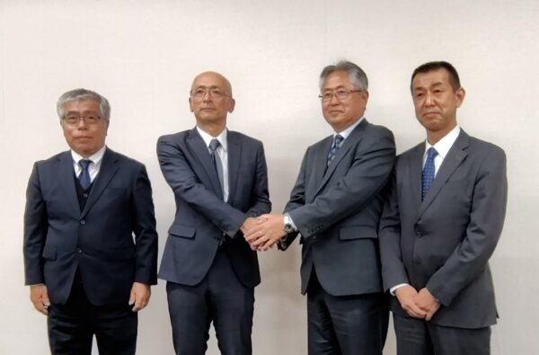  協定書に調印後、握手する読売新聞大阪本社の紀之定映精常務取締役制作局長（右から2人目）と山陰中央新報社の壷倉真司常務取締役総務局長（同3人目）