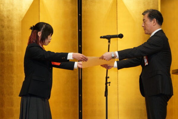  文部科学省初等中等教育局・田村学主任視学官から表彰状を授与される受賞者の嘉納さん